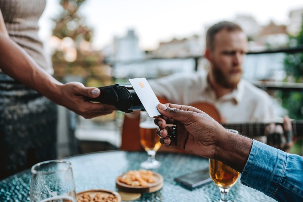 two people at restaurant using a credit card while discussing the basics of credit from Amerant Bank