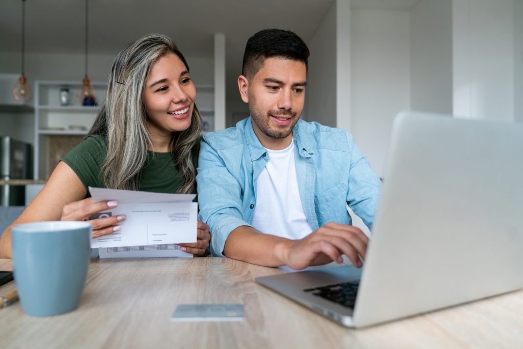 financial planning for couples sitting at their table with a laptop holding a bill