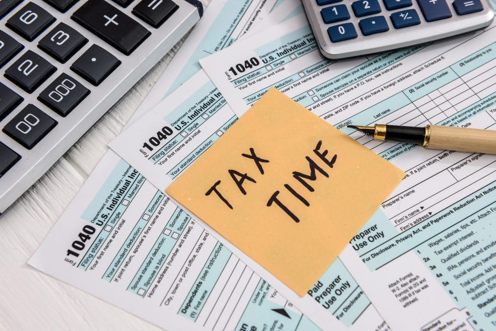 a stack of tax filing documents with a tax time note on it as amerant bank shares how to prepare for tax season