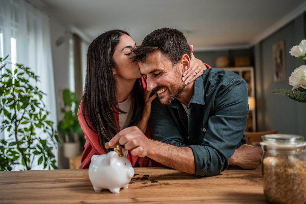 A Couple's Guide to Financial Success as man puts money in piggy bank with woman kissing the cheek