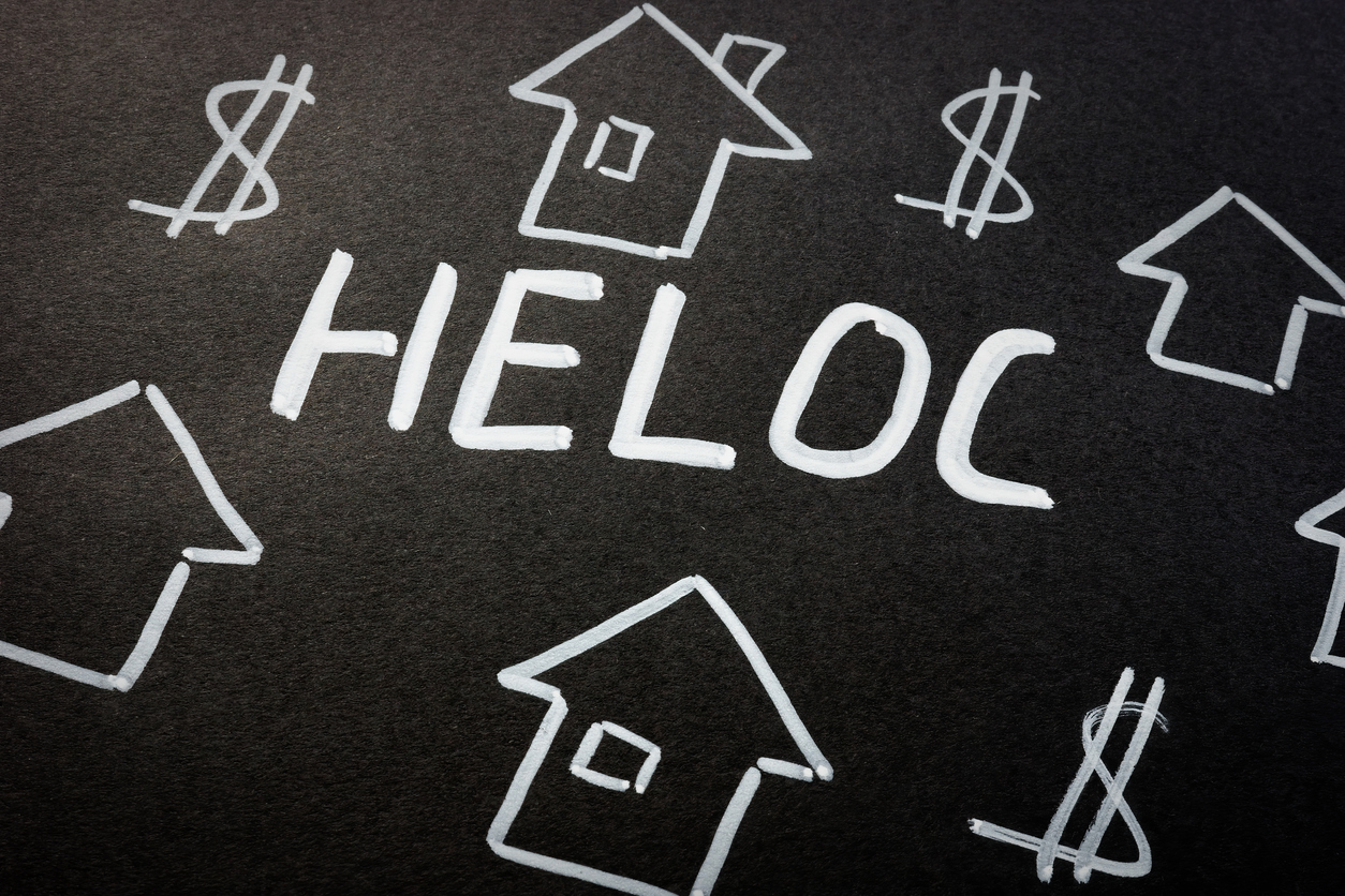 Chalk drawings of houses and the American money sign with the word HELOC in the middle of the board - HELOC vs Credit Cards